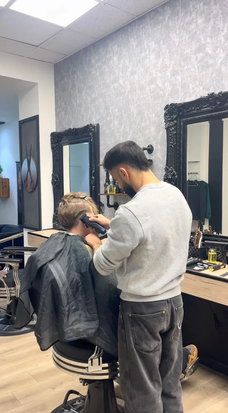 Barber schneidet einem Kunden im Salon die Haare mit der Maschine
