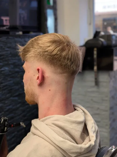 Ansicht schräg von hinten: blonder Kurzhaarschnitt mit Fade